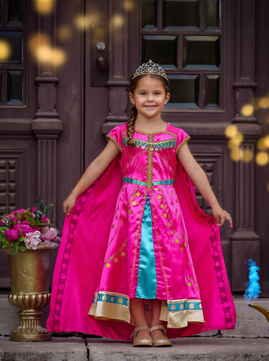 Girl in a Jasmine-inspired dress from Aladdin, standing on steps with a tiara, next to a vase of flowers and a magic lamp.